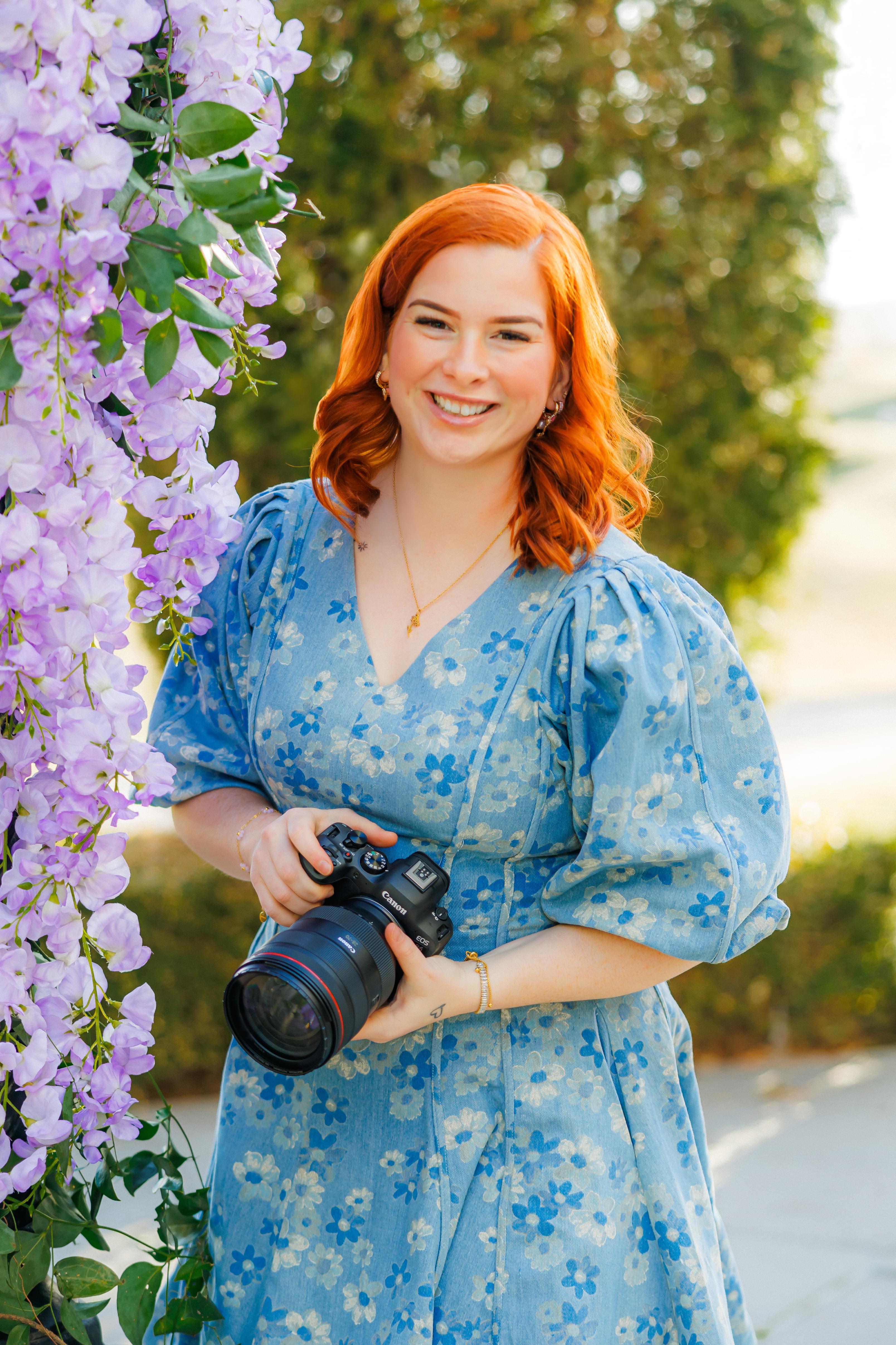 Woman holding a camera surrounded by flowers